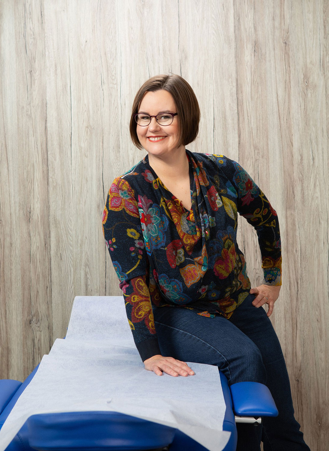 Kiinalaisen lääketieteen taitaja, hymyilevä Hanna-Leena Heikkilä istuu hoitopöydän reunalla